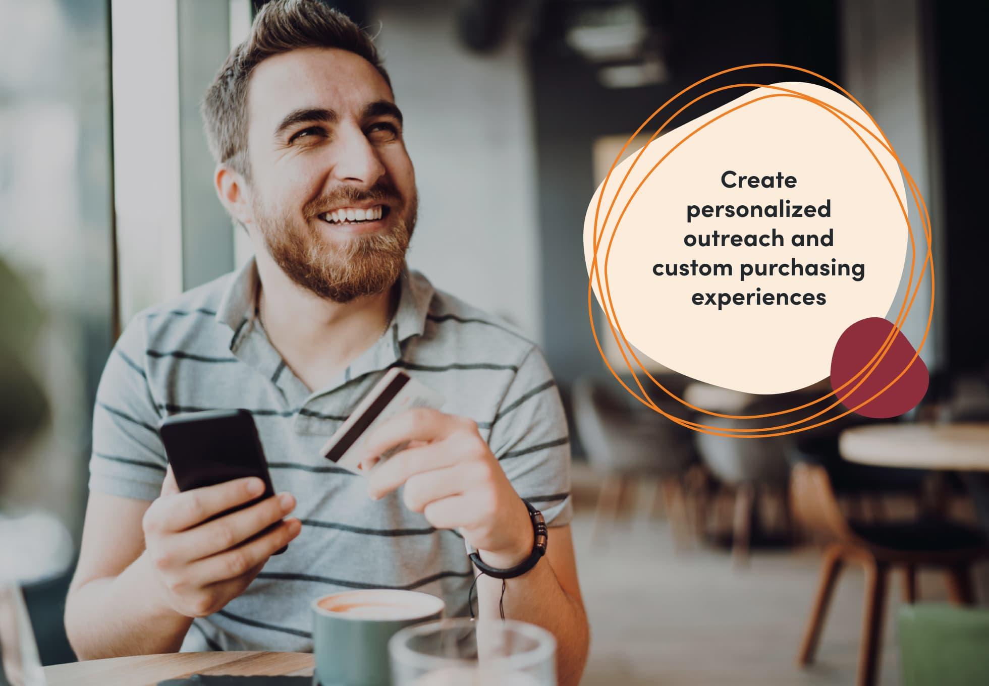 A person in a coffee shop holding their cellphone in one hand and a credit card in another. A sentence imposed on top of the image says, "Create personalized outreach and custom purchasing experiences."